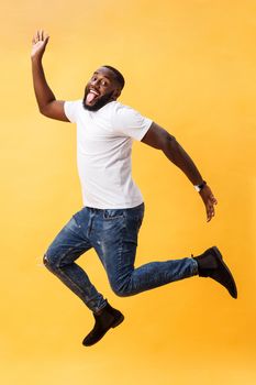 Full length of handsome young black man jumping against yellow background