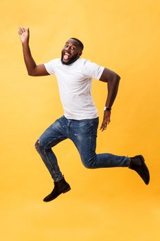 Full length of handsome young black man jumping against yellow background