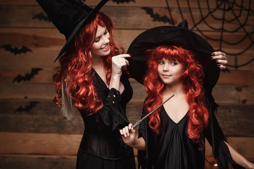 Halloween Concept - Beautiful caucasian mother dress up for her daughter in witch costumes and long curly hair ready for celebrating Halloween