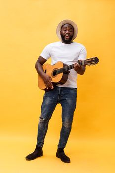 Full-length photo of excited artistic man playing his guitar in casual suite. Isolated on yellow background