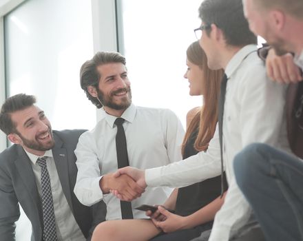 young business people shaking hands while sitting in the office lobby . business concept