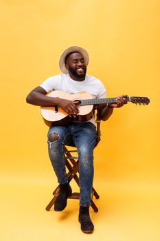 Full-length photo of excited artistic man playing his guitar in casual suite. Isolated on yellow background