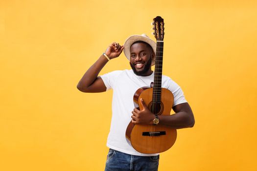 Muscular black man playing guitar, wearing jeans and white tank-top. Isolate over yellow background