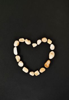  Heart shape with pebbles on black background , passion and love