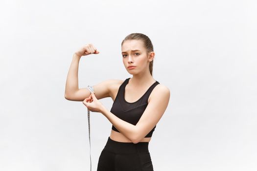 Portrait of an upset sad woman holding measuring tape looking at camera isolated over white background.