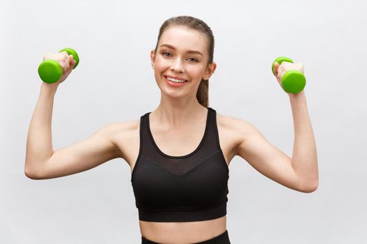 Happy fitness woman lifting dumbbells smiling cheerful, fresh and energetic. Caucasian fitness girl training isolated on white background