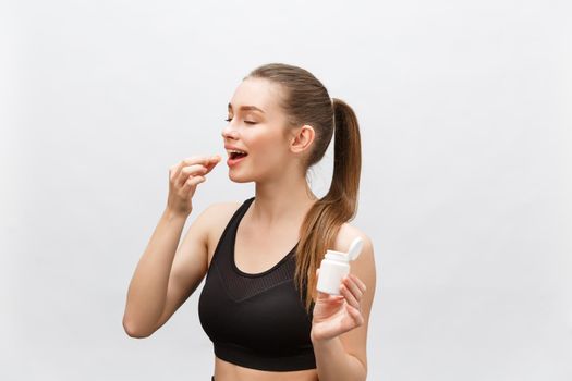 Smiling blonde sport woman holding bottle of medicine on white background.