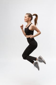 Full length picture of happy beautiful fitness woman over gray background.