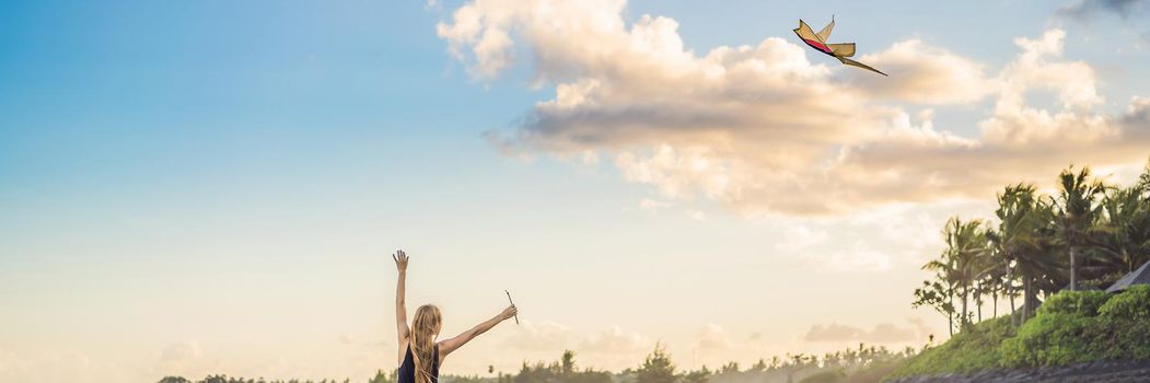 A young woman launches a kite on the beach. Dream, aspirations, future plans. BANNER, LONG FORMAT