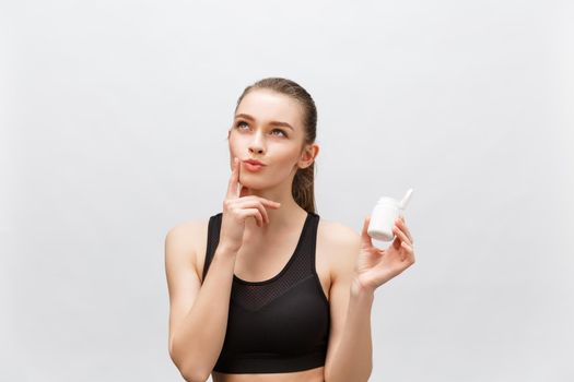 Smiling blonde sport woman holding bottle of medicine on white background.