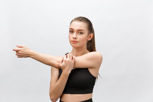 Young sporty beautiful woman stretching arms on side. Isolated over white background.