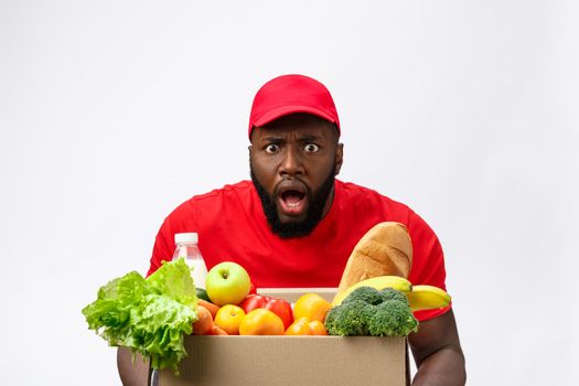 Young african american man holding grocery box in hands with shocking face. Isolated over Grey background