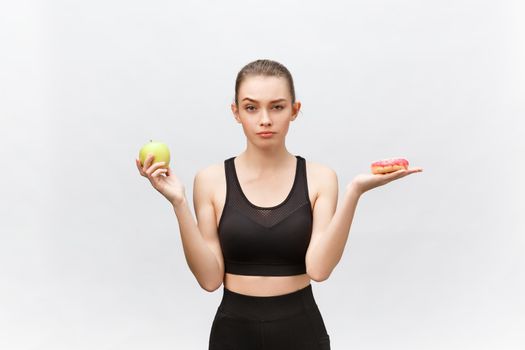 Young woman choosing between donut and apple on white background. Diet food concept.