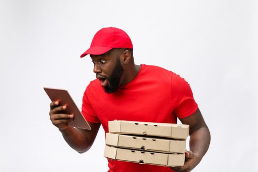 Delivery Concept: Handsome african pizza delivery man talking to mobile with shocking facial expression. Isolated over grey background