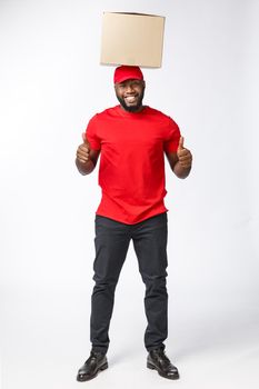 Delivery Concept - Portrait of Happy African American delivery man holding box packages and showing thumbs up. Isolated on Grey studio Background. Copy Space