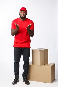 Delivery Concept - Portrait of Happy African American delivery man in red cloth holding a box package. Isolated on Grey studio Background. Copy Space.