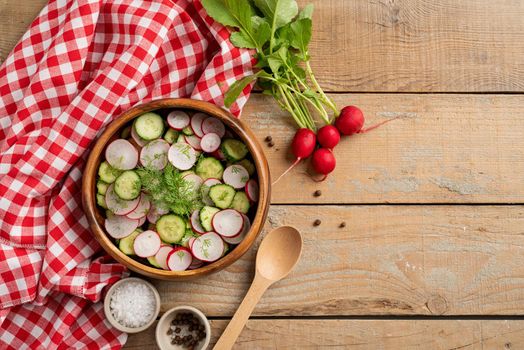 Bowl of healthy vegetarian salad with radish cucumber and fennel. top view on wooden background with copy space, summer food
