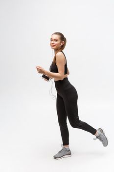 Sport woman. Young beautiful woman in sport clothes. Portrait full length sitting in headphones listening music