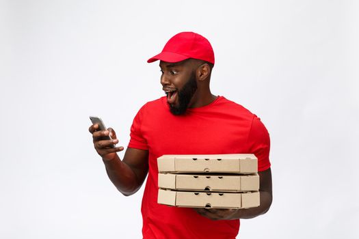 Delivery Concept: Handsome african pizza delivery man talking to mobile with shocking facial expression. Isolated over grey background