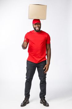 Delivery Concept - Portrait of Happy African American delivery man holding box packages and showing thumbs up. Isolated on Grey studio Background. Copy Space