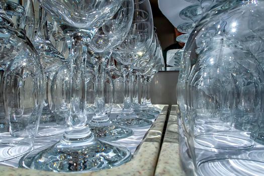 Rows of empty wine glasses close up. Glass goblets on the white table. Restaurant bar concept