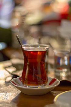 Hot Turkish tea with spoon outdoors on the table. Turkish tea and traditional Turkish culture concept. Vertical. Close up