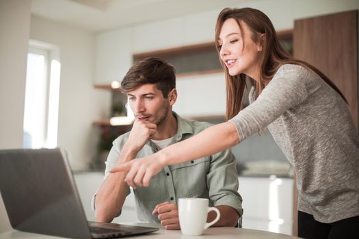 Young couple looking discussing online news in the kitchen. people and technology