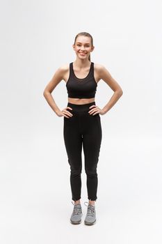 Attractive young adult in sportswear posing on white background. Sexy and sensual brunette woman with perfect body posing in studio isolated over white background with copyspace.