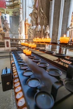 Candles in the Church. Votive prayer candles inside a catholic church on a candle rack.