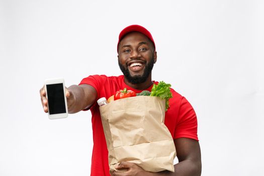 Delivery Concept - Portrait of Handsome African American delivery man or courier showing mobile phone on you to check the order. Isolated on Grey studio Background. Copy Space.