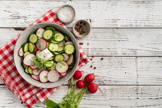 Bowl of healthy vegetarian salad with radish cucumber and fennel. top view on wooden background with copy space, summer food