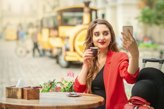 Female tourist is taking self portrait by smart phone at cafe outdoors.