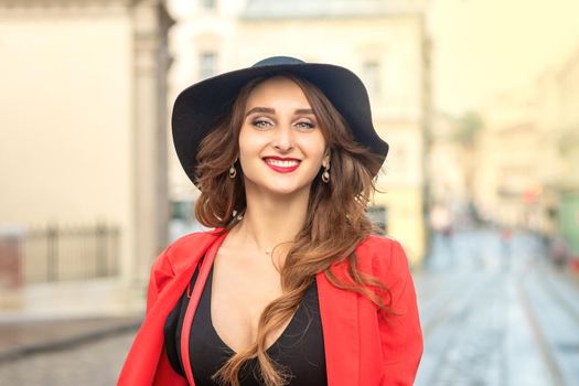 Outdoor portrait of young elegant fashionable woman wearing trendy hat walking in street of European city.