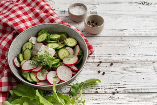 Bowl of healthy vegetarian salad with radish cucumber and fennel. top view on wooden background with copy space, summer food