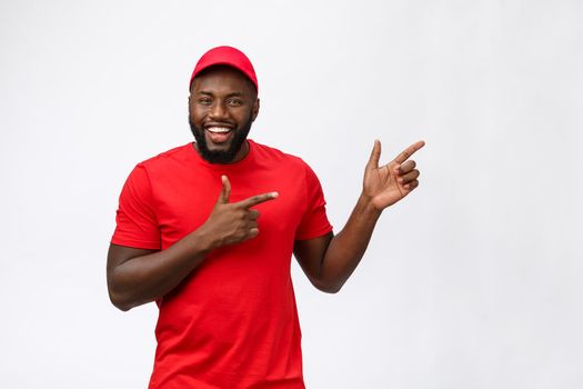 Delivery Concept - Portrait of Happy African American delivery man pointing hand to present something. Isolated on Grey studio Background. Copy Space.