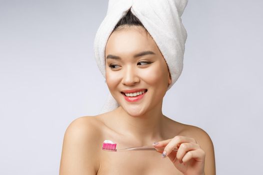 Beautiful young woman on white isolated background holds a toothbrush, Asian.