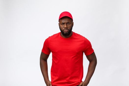 Delivery Concept - Portrait of Serious African American delivery man showing silly aggressive expression and unhappy. Isolated on Grey studio Background. Copy Space