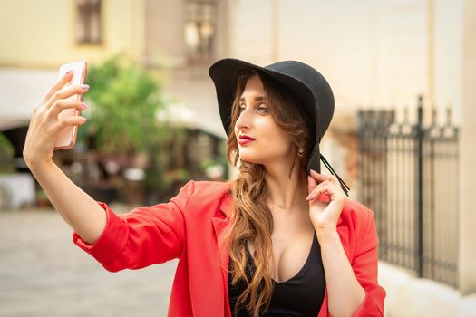 Happy young travel woman is taking selfie on the street of old European city.