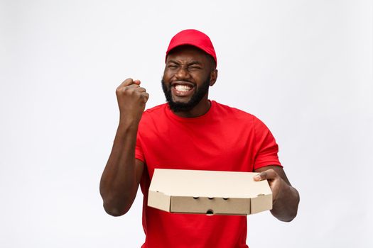 Photo of happy african american man from delivery service in red t-shirt and cap giving food order and holding pizza boxes isolated over white background.