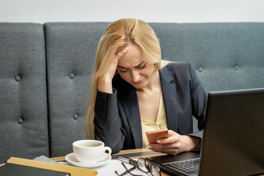 Woman looking surprised while using smartphone at the workplace at home.