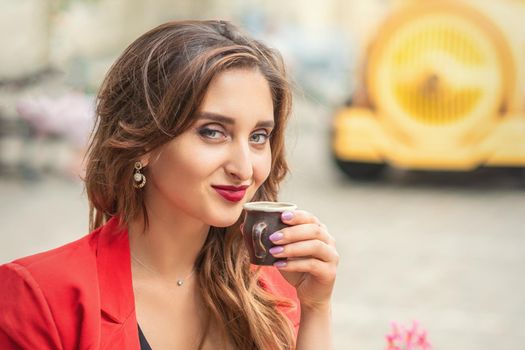 Close up portrait of young woman drinking coffee in a cafe outdoors.