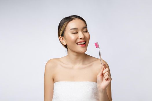 Beautiful young woman on white isolated background holds a toothbrush, Asian.