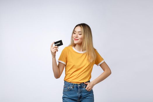 Asian content woman holding fan of money dollar banknotes and credit card and looking on copyspace isolated over gray background