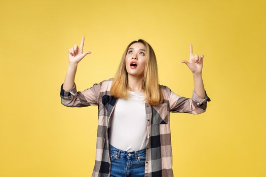 Smiling woman pointing finger side. Isolated portrait on yellow