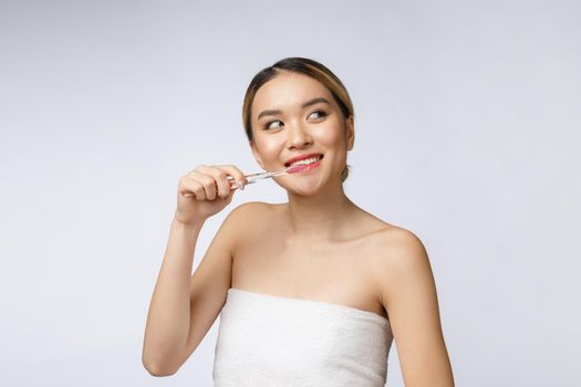 Beautiful young woman on white isolated background holds a toothbrush, Asian.