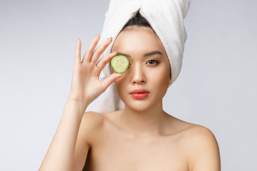 Young asian woman with cucumber slice in her hands isolated on white background