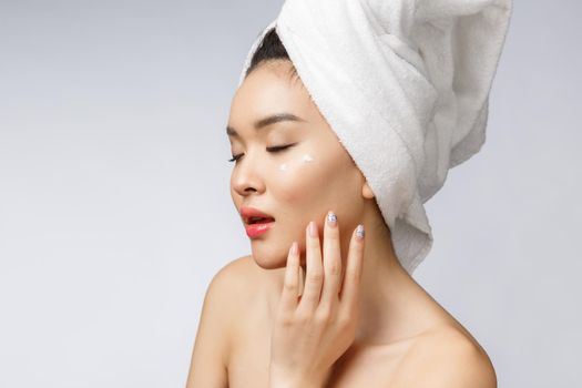 health and beauty concept - Attractive asian woman applying cream on her skin, isolated on white