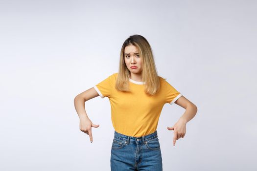 Young Asian woman looking angry and sad while pointing finger at camera isolated against white background