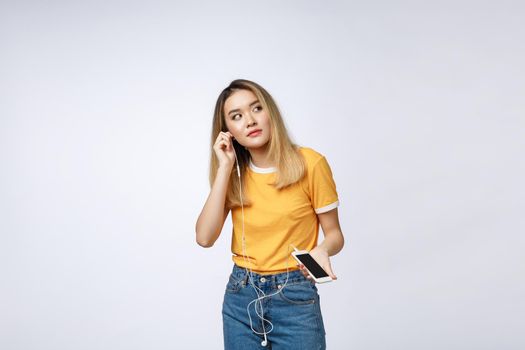 Portrait of a joyful satisfied asian woman in headphones listening to music and jumping isolated over white background.