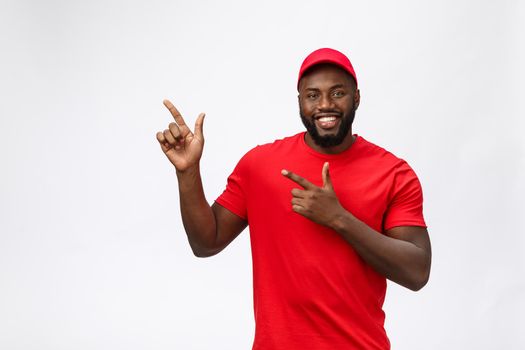 Delivery Concept - Portrait of Happy African American delivery man pointing hand to present something. Isolated on Grey studio Background. Copy Space.